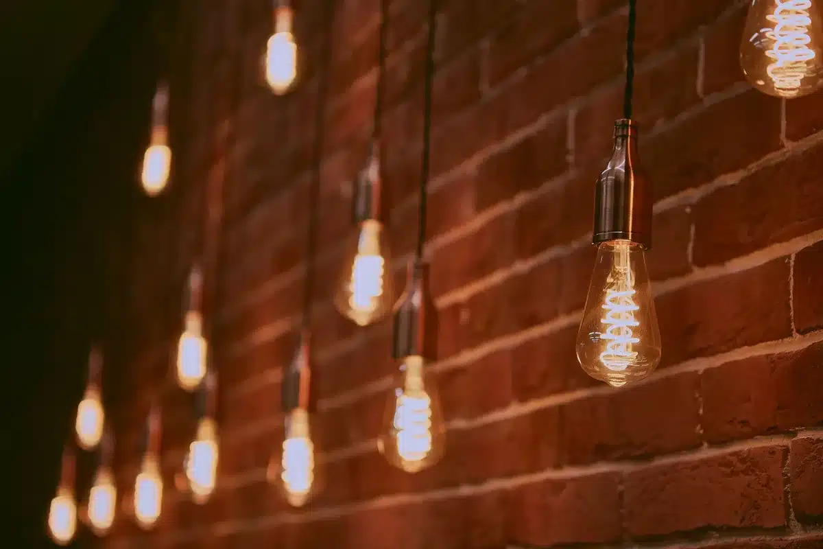 Ampoule LED chaude allumée dans un luminaire, créant une ambiance conviviale sur terrasse