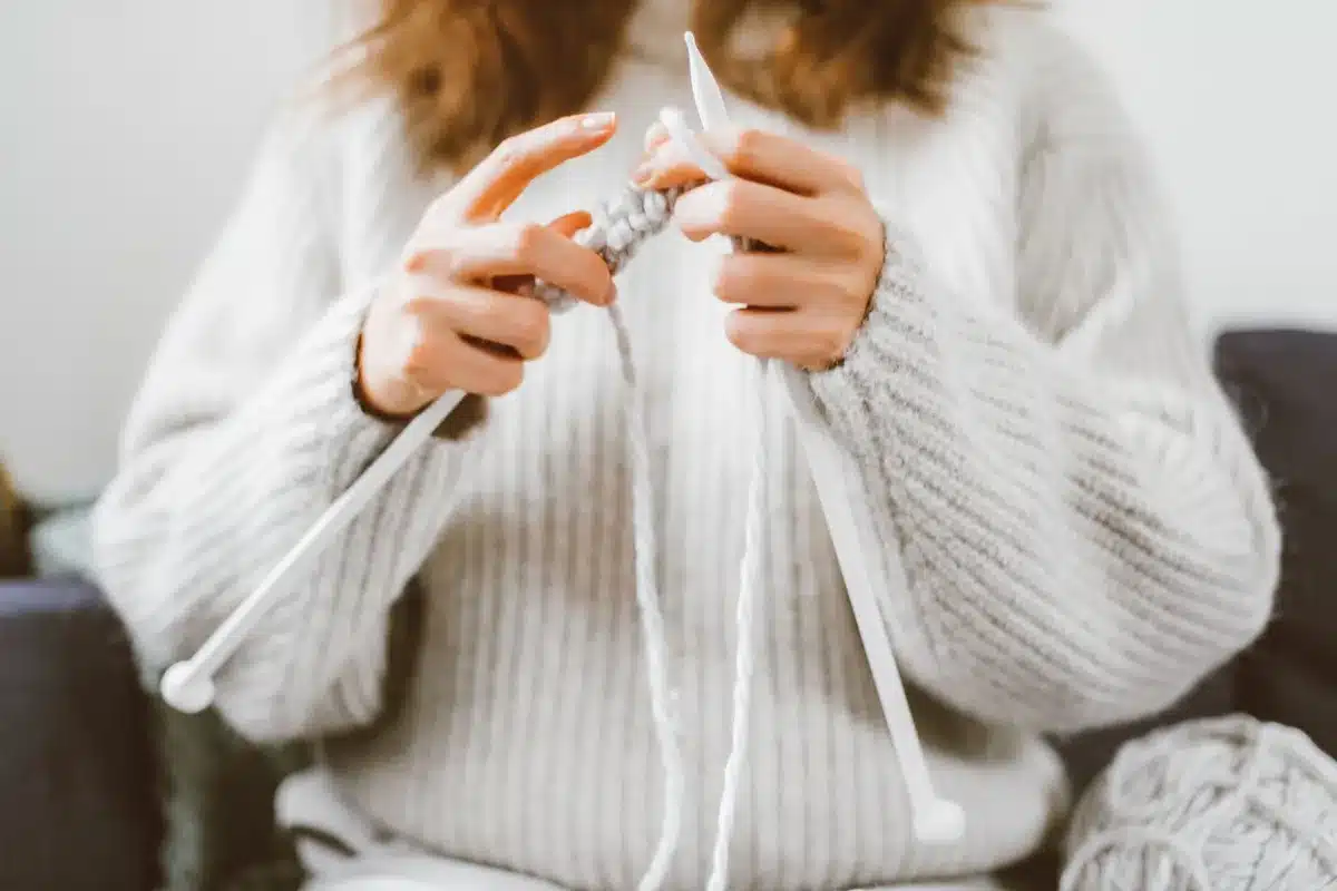 Détail d'un pull en cours de tricot montrant les emmanchures et la technique de diminution progressive.